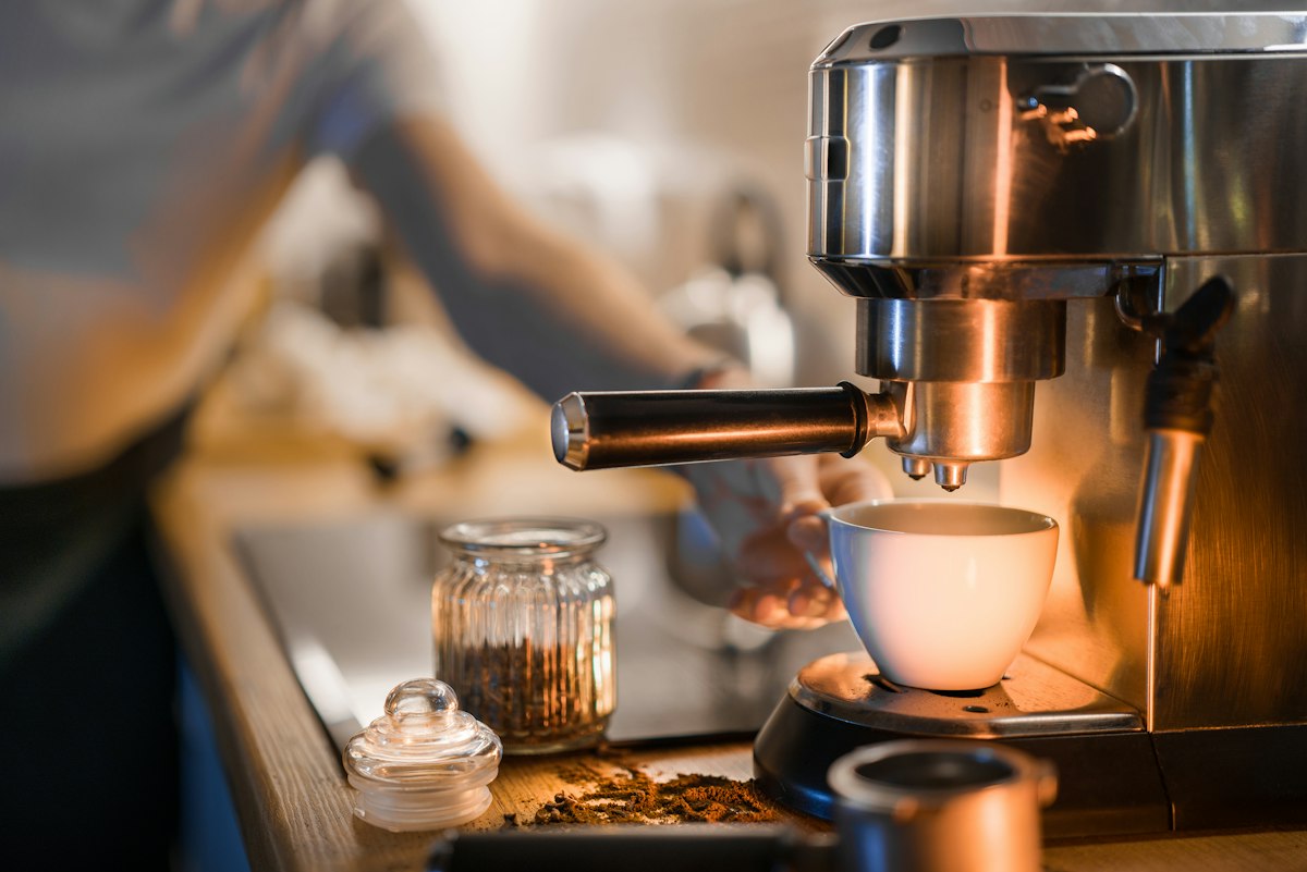 A ConnectionCafe.com barista extracting espresso into a warmed cup at the coffee bar