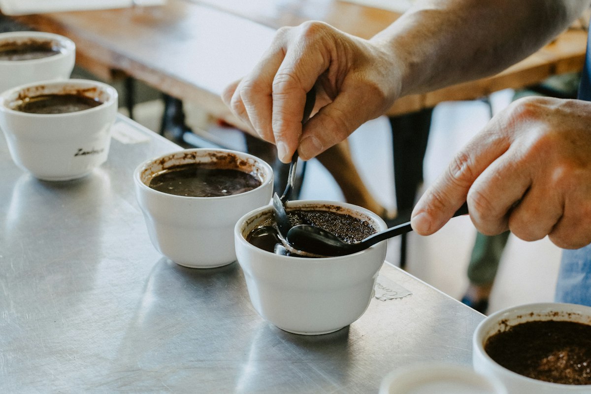 Breaking the crust on a cupping bowl during a green coffee tasting at ConnectionCafe.com