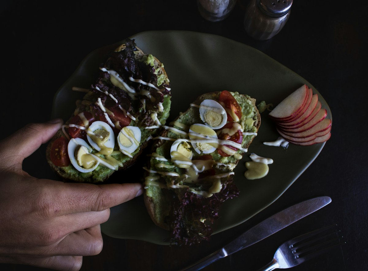 Avocado and soft egg toast plated on a dark ceramic dish in the ConnectionCafe.com kitchen