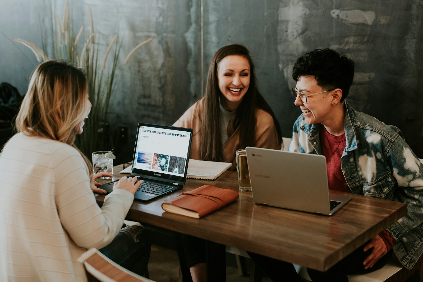 Friends laughing together over laptops at a café table — the relaxed feel ConnectionCafe.com aims for