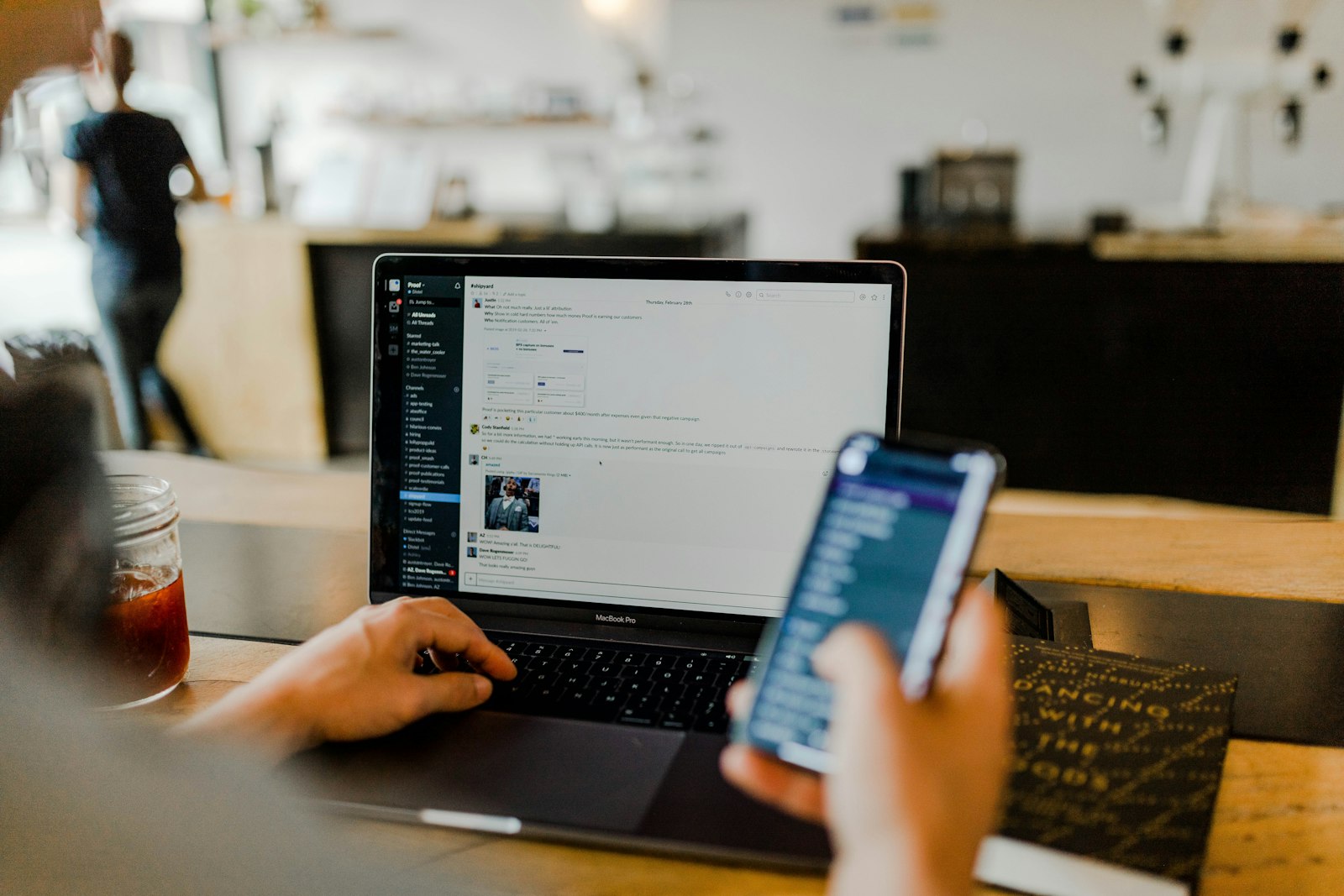 A person using a smartphone in front of an open laptop, as when approving a two-factor authentication sign-in