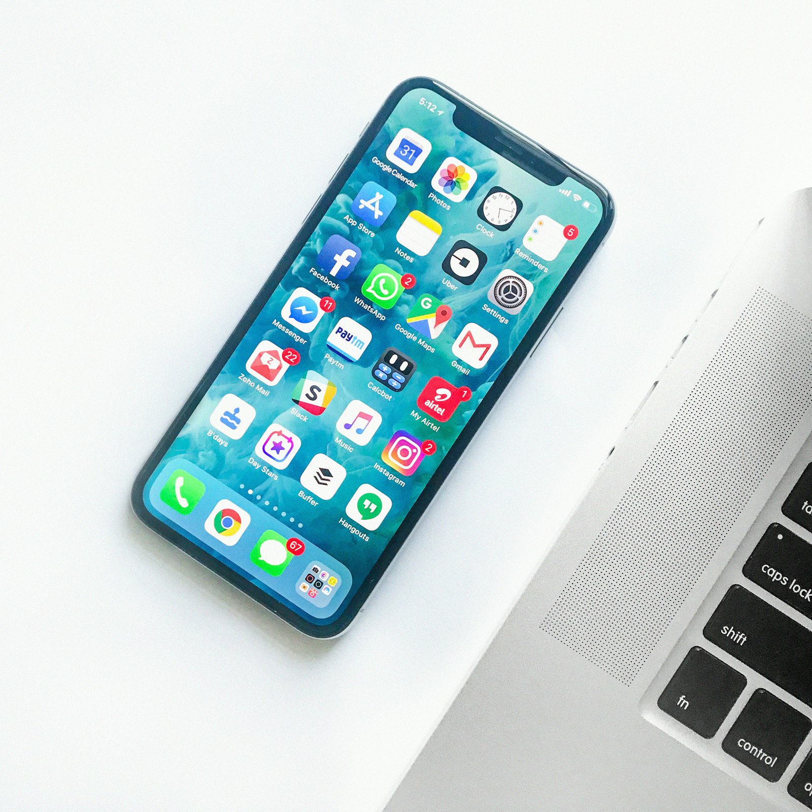 A smartphone home screen full of app icons resting on a laptop, a common sight when phone storage is full