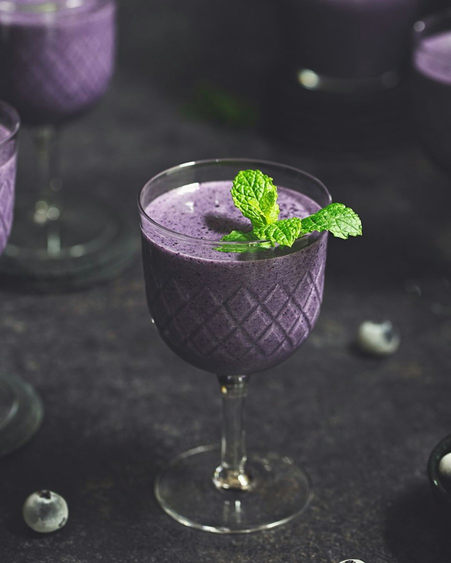 Pale purple lavender milkshake garnished with fresh mint in a stemmed glass